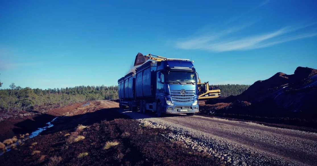 Sävne Torvs blåa lastbil som lastas med torv en vacker sommardag
