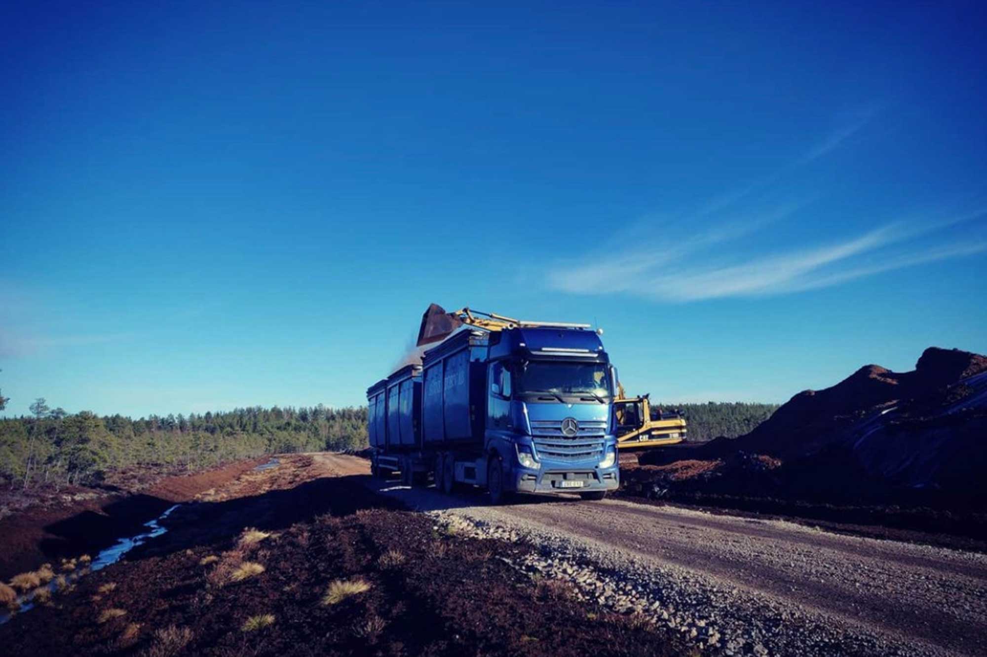 Sävne Torvs blåa lastbil som lastas med torv en vacker sommardag